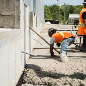 two men in orange vests working on a building